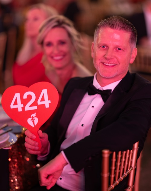 Couple holding up bidder paddle number 424.